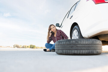 Woman calling a mechanic to change her car flat tire