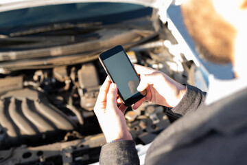 Latin man texting a mechanic on the roadside
