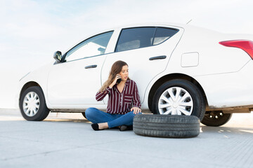 Attractive woman stranded on the roadside because of a flat tire