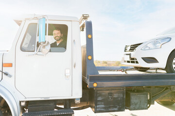 Male operator smiling and driving a tow truck