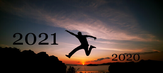 New year 2021 concept of Silhouette travel man jumping on the cliff in sunrise or sunset time to 2021 new year,image for happy new year background.