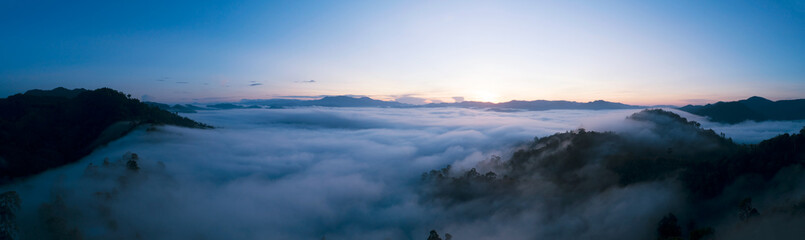 Panorama Aerial view Drone shot of Beautiful scenery landscape sunlight in the morning sunrise above flowing fog waves on mountain peak tropical rainforest in phang nga thailand