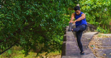 athletic sport man stretching after jogging workout outdoors in park