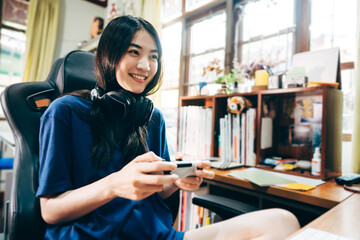 Young adult asian woman hand holding a joy controller wear headset and play game at home