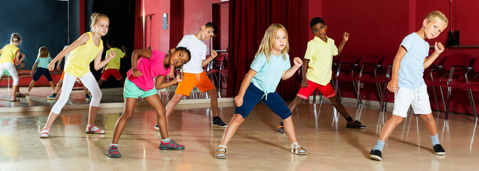 Positive kids studying modern style dance in class indoors