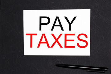 PAY TAXES .notebooks and a pen on the table for information. . Business, marketing, financial concept