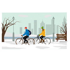 A girl and a guy ride bicycles in the park. in the background winter cityscape.