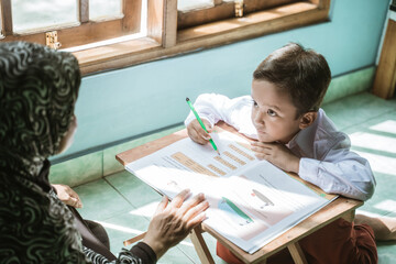 mother help her child doing homework. indonesian elementary student at home