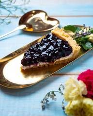Portion of sliced cheesecake with black currant and blueberry sauce on wooden table