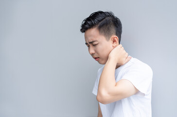 Young man is frowning painfully with hand over his neck 