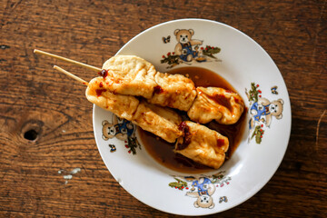 Top view snack vegan food (fried tofu with sauce) in white ceramic plate on wooden background. Thai and Chinese people popular eaten vegan foods in Chinese vegetarian festival in October every years.