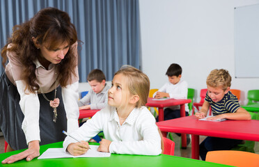 Fototapeta premium Portrait of young teacher woman at lesson with diligent school kids..