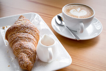 Croissant with coffee latte on wooden floor