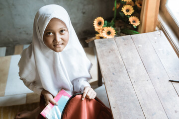 primary indonesian school student preparing her book at home before going to school in the morning