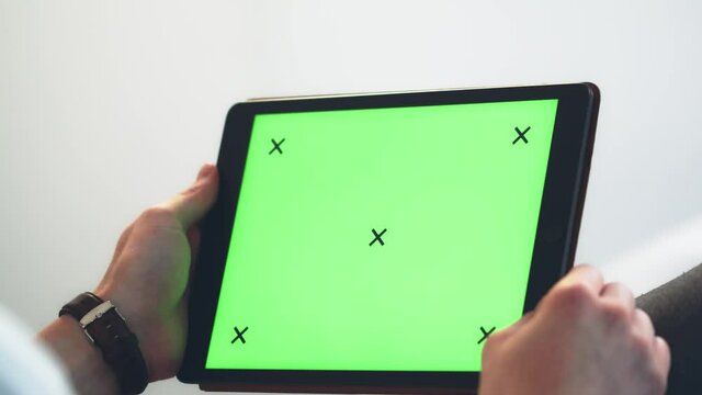 Concept for video chat, website and application. Close-up shot of caucasian man holding a tablet with green screen chroma key screen in his hands. Filmed in 4k.