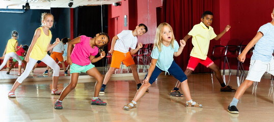 Positive smiling children studying modern style dance in class indoors