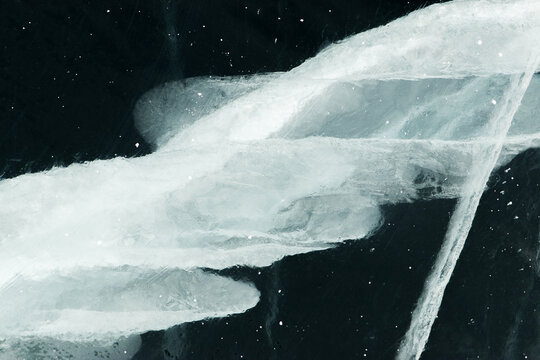 Abstract texture of broken white ice and dark water at winter. Cracked ice.