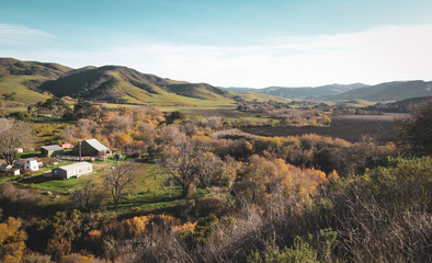 Fototapeta na wymiar A rural farm with a barn and home and a field in the hills of central California on a sunny day in autumn