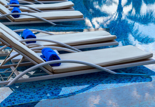 Sun terrace equipped with umbrellas and deckchairs and towels by the pool of clear blue water views.