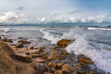 Fototapeta na wymiar Empty rocky beach and stormy sea in cloudy weather