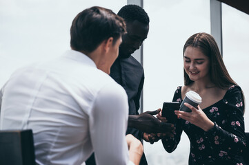 Multiracial friends sitting in cafe enjoying coffee during work break, listening to Caucasian male talking and sharing thoughts, diverse colleagues meeting in coffeeshop discussing business project