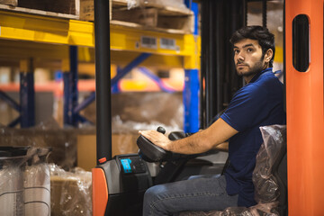 Young forklift driver sitting in vehicle in warehouse