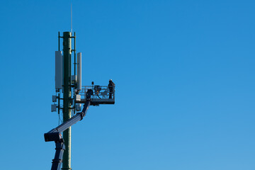 Telecommunications tower with 4G, 5G transmitters, Worker on cellular base station with...