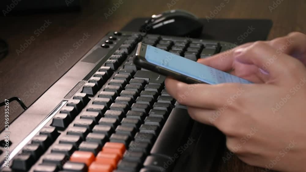 Poster writing emails on the smartphone and typing on the computer desktop keyboard.working from home conce