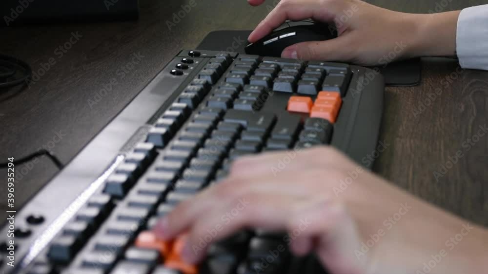 Poster playing games on the computer, using the mouse and the keyboard.focus on the wireless computer mouse