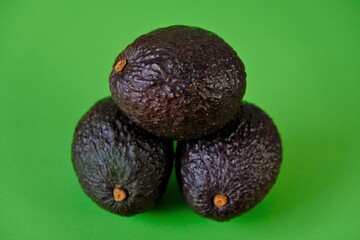 Ripe avocado set. Dark brown avocado fruit on a bright green background. Eco-friendly organic farm product. Vegan and vegetarian food. Super food.
