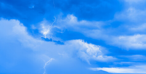 Lightning strikes between stormy clouds.