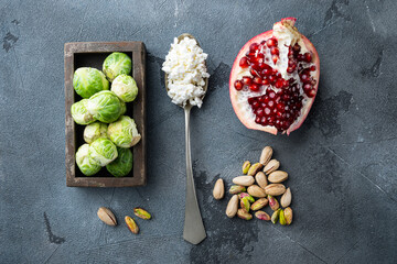Obraz na płótnie Canvas Brussels sprouts, with pomegranate, cottage cheese and pistachios, on grey background, flat lay
