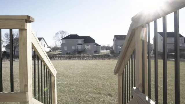New wooden deck with stairs that walk out to a grass filled back yard.