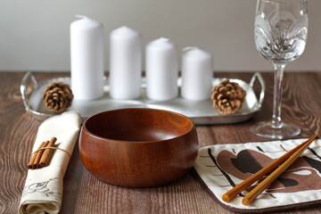 Rustic table layout with wooden bowl and candles on wooden background
