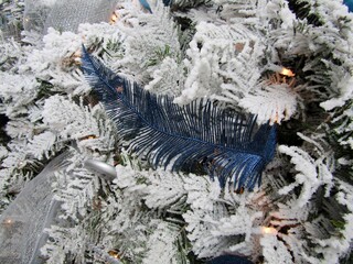 Large glitter feathers decoration on white Christmas tree.
