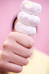 Delicious doughnuts sprinkled with powdered sugar embedded in the thumb of a hand with a person on the back.