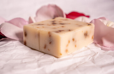 Handmade rose soaps decorated with rose petals on a white background.