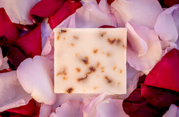 Handmade rose soaps decorated with rose petals on a white background.