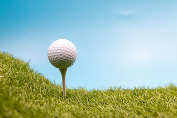Golf ball is on tee on blue sky background