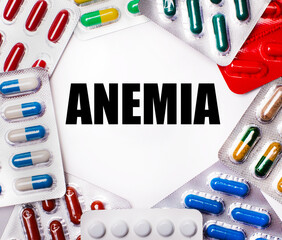 ANEMIA is written on a light background surrounded by multi-colored packages with pills. Medical...