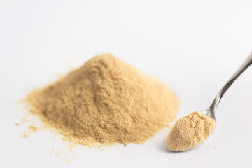 Sunflower lecithin heap with a spoon on a light background.