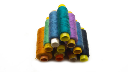A pyramid of various colors of sewing thread roll on an isolated white background.