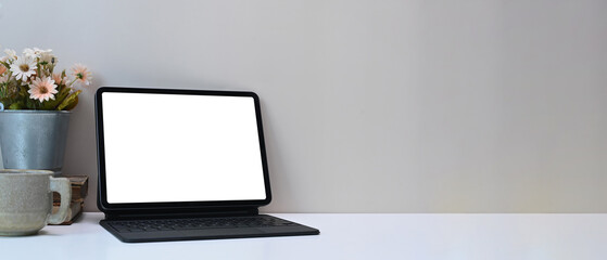Minimal workspace with white blank screen monitor computer tablet, plant, coffee cup and copy space on white desk.