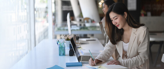 Two attractive business woman are working together in modern office.