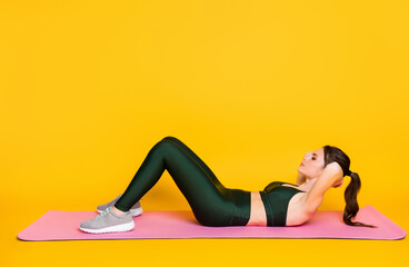 Profile side full body view of nice thin slender focused girl lying on mat doing crunches isolated on bright yellow color background
