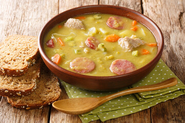 Winter pea soup with vegetables, sausages and pork close-up in a bowl on the table. horizontal
