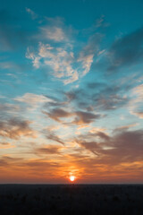 Fototapeta premium Natural Sunset Sunrise Over a forest or meadow. Bright beautiful sky and dark earth. Small clouds. Frosty winter morning.