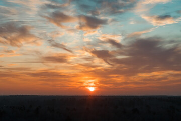 Natural Sunset Sunrise Over a forest or meadow. Bright beautiful sky and dark earth. Small clouds....