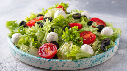 Fresh vegetables salad with tomatoes, mozzarella cheese  and olives.