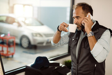 Pensive mechanic talking on the phone while having coffee break in the office.